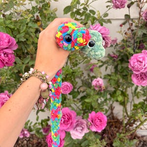Peut inclure: Un jouet en peluche &agrave; deux t&ecirc;tes, l'une avec un motif en laine multicolore vive et l'autre en laine vert clair unie. Les deux t&ecirc;tes sont dot&eacute;es de grands yeux de s&eacute;curit&eacute; en plastique noir. Le corps est form&eacute; d'une longue tresse multicolore.