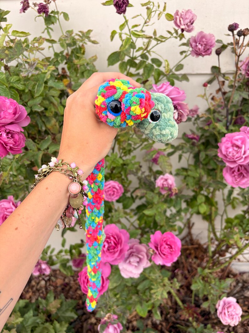 Peut inclure: Un jouet en peluche &agrave; deux t&ecirc;tes, l'une avec un motif en laine multicolore vive et l'autre en laine vert clair unie. Les deux t&ecirc;tes sont dot&eacute;es de grands yeux de s&eacute;curit&eacute; en plastique noir. Le corps est form&eacute; d'une longue tresse multicolore.