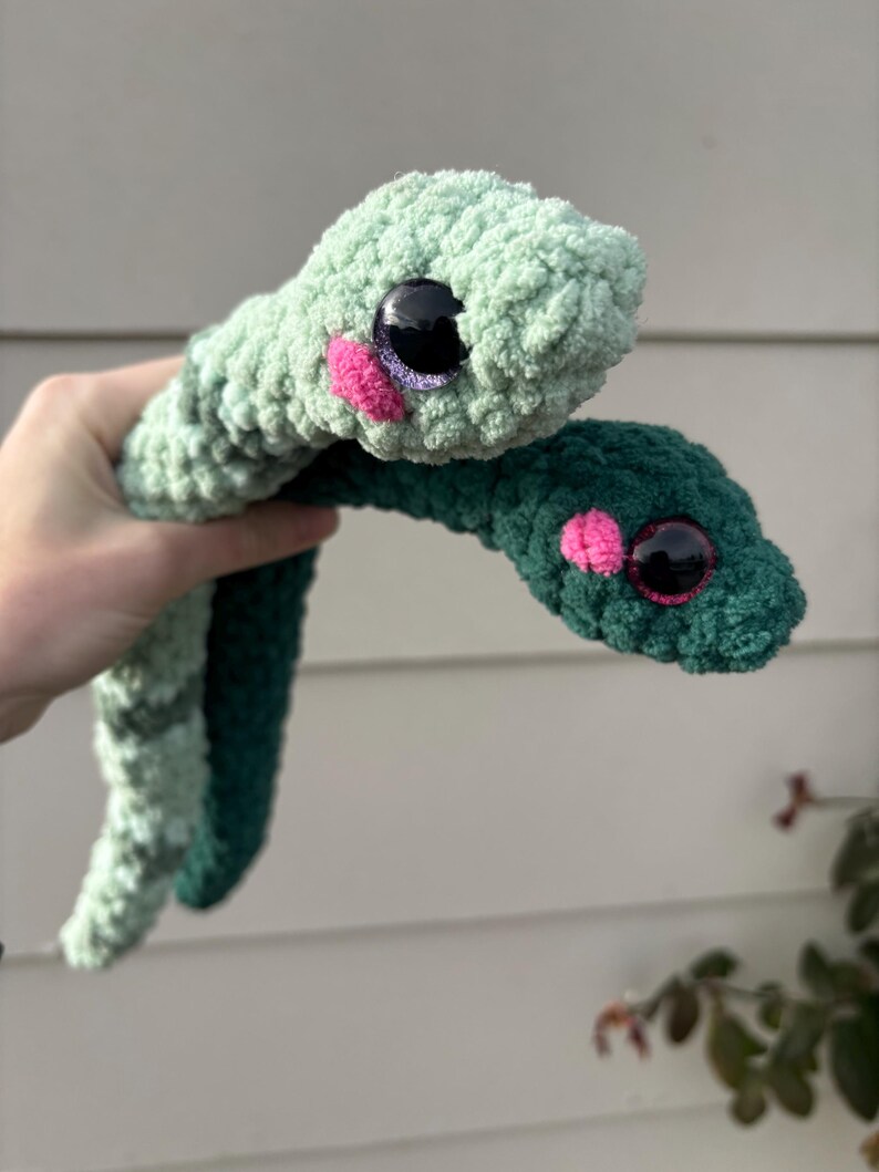 Peut inclure: Deux serpents en peluche fabriqu&eacute;s en fil textur&eacute; doux. L'un est vert menthe clair et l'autre est vert for&ecirc;t fonc&eacute;. Ils poss&egrave;dent tous deux de grands yeux ronds en plastique noir avec des reflets violets et de petites joues en laine rose vif.