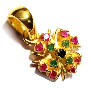 May include: Gold pendant with a flower design featuring red, green and black gemstones.