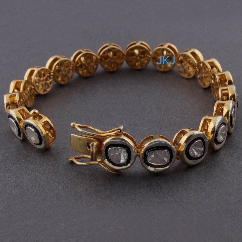 May include: A gold bracelet with a clasp closure. The bracelet is adorned with oval-shaped diamonds set in a gold and white metal frame. The bracelet is a classic and elegant piece of jewelry.