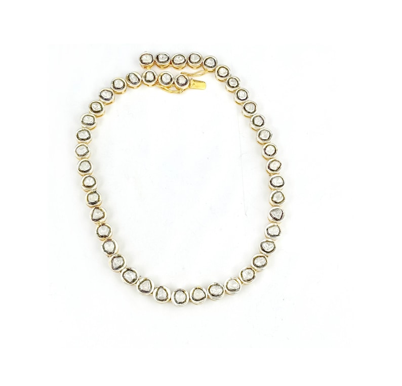 May include: A gold chain necklace with a row of round, clear, faceted diamonds.