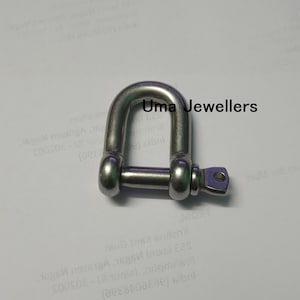 Könnte beinhalten: Ein D-Schäkel aus Edelstahl mit gewölbter Oberseite und abnehmbarem Stift. Der Schäkel hat eine polierte Oberfläche und der Text "Uma Jewellers" ist sichtbar.