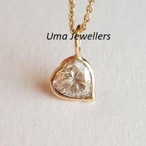 Op de afbeelding: Een gouden hartvormige hanger met een heldere diamant in het midden. De hanger zit aan een gouden ketting.