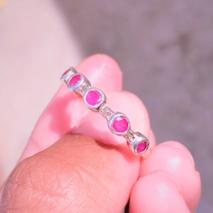 Peut inclure: Une bague en argent avec des pierres rondes rouges rubis et claires alternées.
