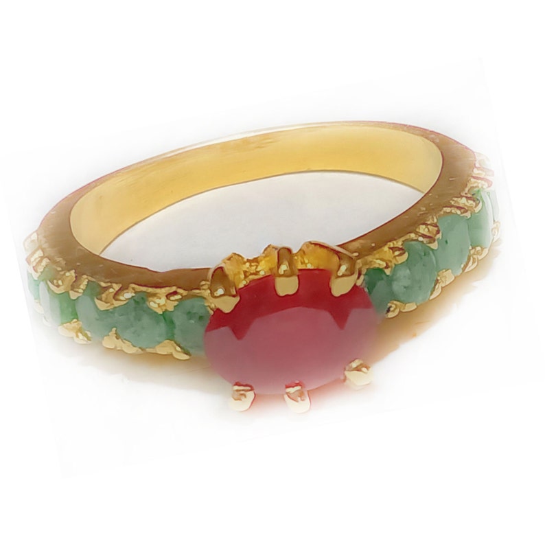 May include: A gold ring with a red gemstone surrounded by green gemstones.