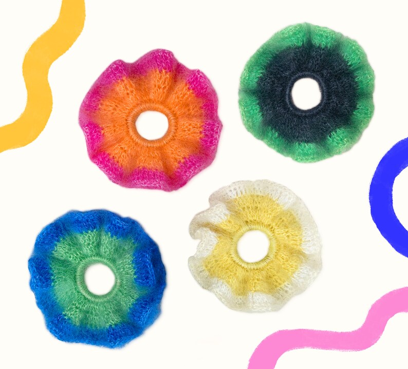 May include: Four colorful, fluffy scrunchies in shades of orange, pink, green, blue, and yellow. Each scrunchie has a ruffled edge and a circular center. The scrunchies are set against a white background with abstract colorful shapes.