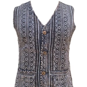Peut inclure: Un gilet sans manches avec un motif géométrique noir et blanc. Le gilet a un col en V et cinq boutons marrons sur le devant.