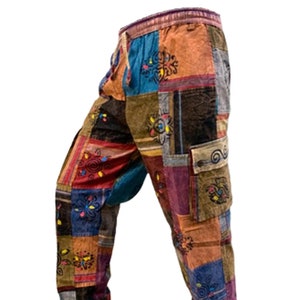 May include: Multi-coloured patchwork trousers with a drawstring waist. The trousers feature a mix of teal, brown, and purple patches. Floral embroidery decorates the patchwork. A cargo pocket is visible on the right leg.