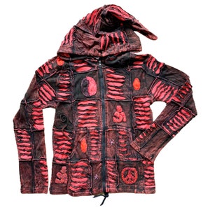 Op de afbeelding: Een rode en zwarte patchwork hoodie met een ritssluiting en een capuchon. De hoodie heeft verschillende geborduurde ontwerpen, waaronder een yin yang symbool, een vredesteken en een gestileerde figuur.