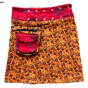 May include: A red and yellow mini skirt with a circle pattern. The skirt has a red pocket with a zipper and black trim.