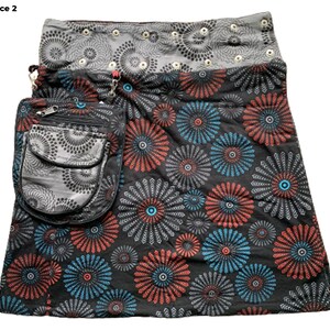 May include: A black skirt with a colorful floral print. The skirt has a large pocket on the side and a gray waistband with silver grommets.
