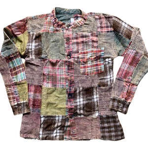 May include: A long-sleeved patchwork shirt with a button-up front. The shirt is made of different plaid fabrics in shades of brown, green, red, and blue.
