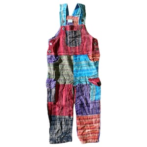 May include: Multicolored patchwork overalls with a blue, red, green, and purple color scheme. The overalls have a bib style with adjustable straps and two large pockets on the front.