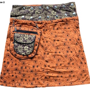 May include: A brown and orange skirt with a floral print and a large pocket on the front. The skirt has a brown waistband with silver studs.