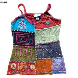 May include: A multi-colored patchwork tank top with embroidered details. The top features a variety of colors, including blue, green, red, orange, and purple. The top is made of a soft, comfortable fabric and has a relaxed fit.