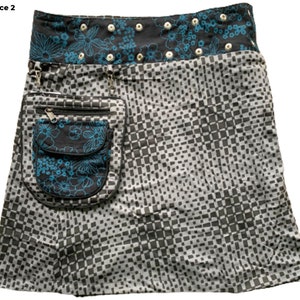 May include: A black and white checkered skirt with a blue and black floral print pocket. The skirt has a black waistband with a blue floral print and silver grommets.