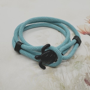 May include: A light blue rope bracelet with a black turtle charm.