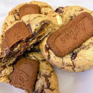 May include: Close-up of four chocolate chip cookies with a caramel filling and a chocolate and caramel biscuit on top. The cookies are on a white plate.