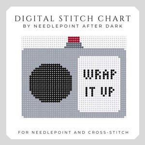 Op de afbeelding: Digitaal kruissteekpatroon met een camera-ontwerp. De camera is grijs met een zwarte lens en een rode knop. De tekst "WRAP IT UP" staat op de zijkant. De tekst "DIGITAL STITCH CHART" en "FOR NEEDLEPOINT AND CROSS-STITCH" zijn ook opgenomen.