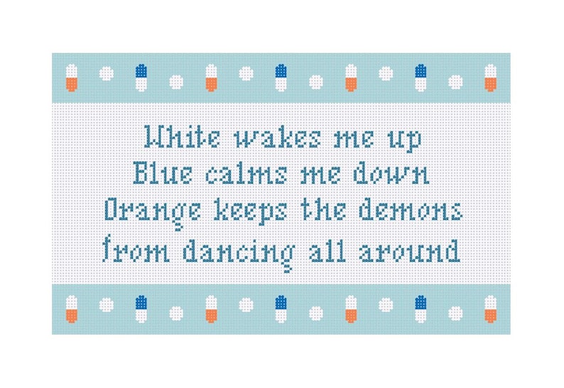 May include: A cross-stitch design on a light blue background. The text reads "White wakes me up, Blue calms me down, Orange keeps the demons from dancing all around." The design includes orange, white, and blue pill-shaped accents.