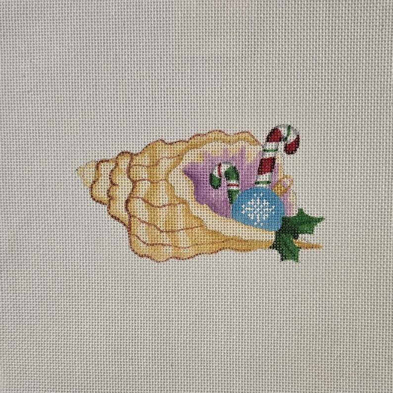 May include: Needlepoint design of a seashell filled with Christmas ornaments. The shell is tan and the interior is lavender. Ornaments include a red and white candy cane, a blue snowflake ornament, and green holly.