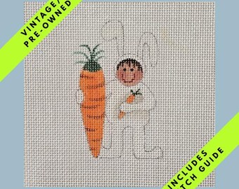 May include: Vintage pre-owned needlepoint canvas featuring a bunny holding a large orange carrot and a smaller carrot. The bunny is wearing a white outfit. Includes stitch guide.