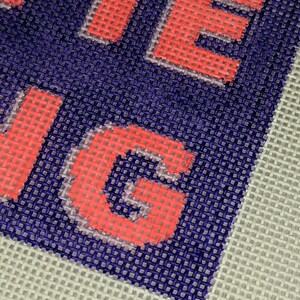 May include: Close-up of a red and white embroidered word "LIVE" on a blue and white canvas background.