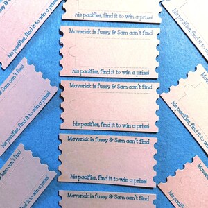May include: Light pink puzzle-shaped cards with blue text. The cards have the text "Maverick is fussy & Sam can't find" and "his pacifier, find it to win a prize!" The cards are arranged on a blue background.