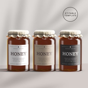 Puede incluir: Tres tarros de vidrio de miel con etiquetas de papel marrón. Cada tarro tiene una tapa de tela blanca y una etiqueta negra con el texto "Honey House Honey" y "Producto de California 100% puro y natural Peso neto 270g/9.5oz Anno 2021".