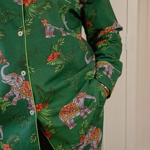 Può includere: Pigiama verde con un motivo ripetitivo di elefanti che indossano copricapi decorati e accenti floreali.