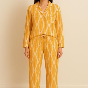 Peut inclure: Ensemble de pyjama deux pièces jaune moutarde avec un motif de feuilles crème. Le haut à manches longues a une fermeture boutonnée et une poche poitrine. Le pantalon a une taille élastique avec cordon de serrage.