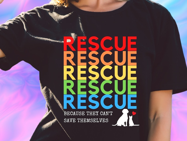 May include: Black t-shirt with a rainbow design that says "RESCUE" five times. The text is in a retro font. Below the text is the phrase "Because they can't save themselves" and a silhouette of a dog and cat.