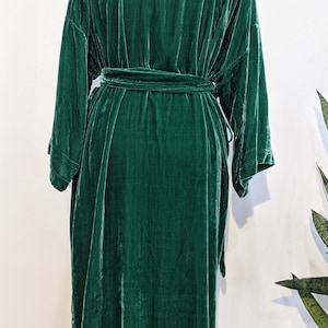 May include: A long, dark green velvet robe with a tie belt. The robe has a relaxed fit and long sleeves.