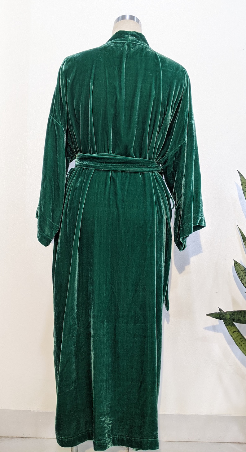 May include: A long, dark green velvet robe with a tie belt. The robe has a relaxed fit and long sleeves.