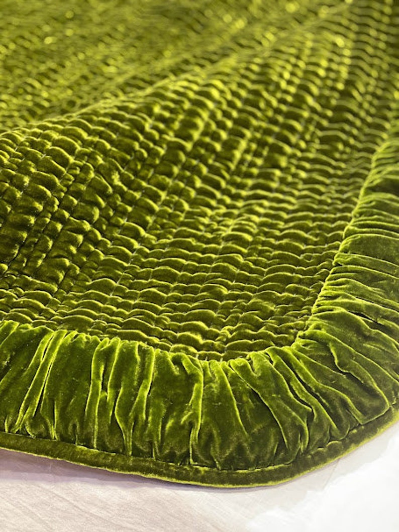 May include: A green velvet quilted throw blanket with a ruffled edge.