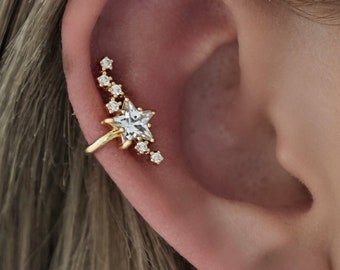 May include: Gold ear cuff with a star-shaped crystal and smaller crystals along the curve of the cuff.
