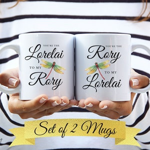 May include: Set of two white ceramic mugs with a dragonfly design and personalized text. The text on the mugs reads "You're the Lorelai to my Rory" and "You're the Rory to my Lorelai".