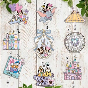 Könnte beinhalten: Eine Sammlung farbenfroher Disney-Pins. Designs umfassen Micky und Minnie Maus, Dumbo, ein Schloss, ein Riesenrad und andere ikonische Disney-Bilder. Die Pins sind an einziehbaren Ausweishaltern befestigt.