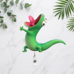 Peut inclure: Un porte-badge vert en forme de lézard de dessin animé avec une langue rose. Le lézard a de grands yeux et est dans une pose ludique. Le porte-badge a une sangle en plastique transparent et un clip en métal.