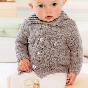 May include: A baby wearing a gray knitted cardigan with button closures and two pockets. The cardigan has a collar and is made with a textured knit.