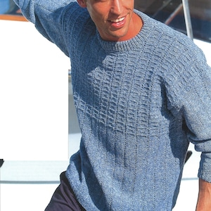 May include: A blue knitted jumper with a textured pattern. The jumper has a crew neck and long sleeves.
