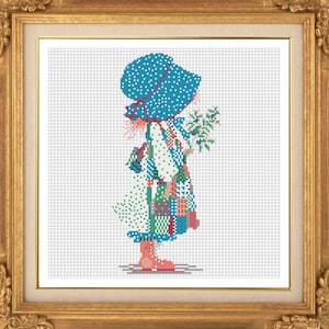 Peut inclure: Point de croix d'une fillette en bonnet bleu et robe patchwork, tenant un bouquet de fleurs. L'œuvre encadrée présente un cadre doré orné. La robe de la fillette est un mélange de couleurs, dont le vert, le rouge et le bleu.