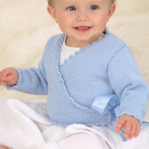 May include: A light blue baby wrap with a white trim and a blue ribbon tied at the waist. The wrap is knitted and has a delicate, feminine look. "Ballerina wrap" is written in the top left corner of the image.