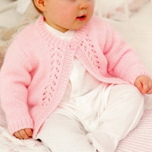May include: A pink knitted baby cardigan with a button closure and a delicate lace pattern on the front.