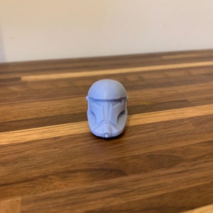 May include: A gray plastic helmet with a detailed design, resembling a Star Wars character.