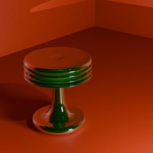 Puede incluir: Un objeto decorativo de vidrio en forma de pesa con una parte superior e inferior redondas. La parte superior e inferior son de color plateado reflectante, mientras que la sección media es de un verde vibrante. El objeto está sobre un fondo rojo anaranjado.