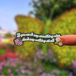 May include: A black sticker with the text "If you can't say something nice, don't say nothing at all" in green and white. The sticker is decorated with purple and white floral accents.