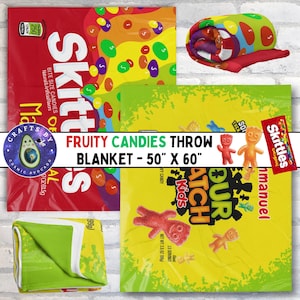 May include: A colorful throw blanket featuring a candy theme. The blanket displays images of Skittles and Sour Patch Kids candies. The blanket measures 50 inches by 60 inches.