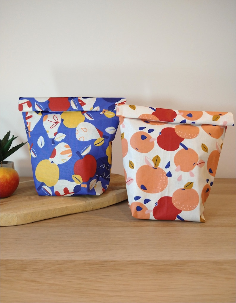 May include: Two reusable fabric bags with a fruit print. One bag is blue with yellow and red fruit, the other is white with orange and red fruit.
